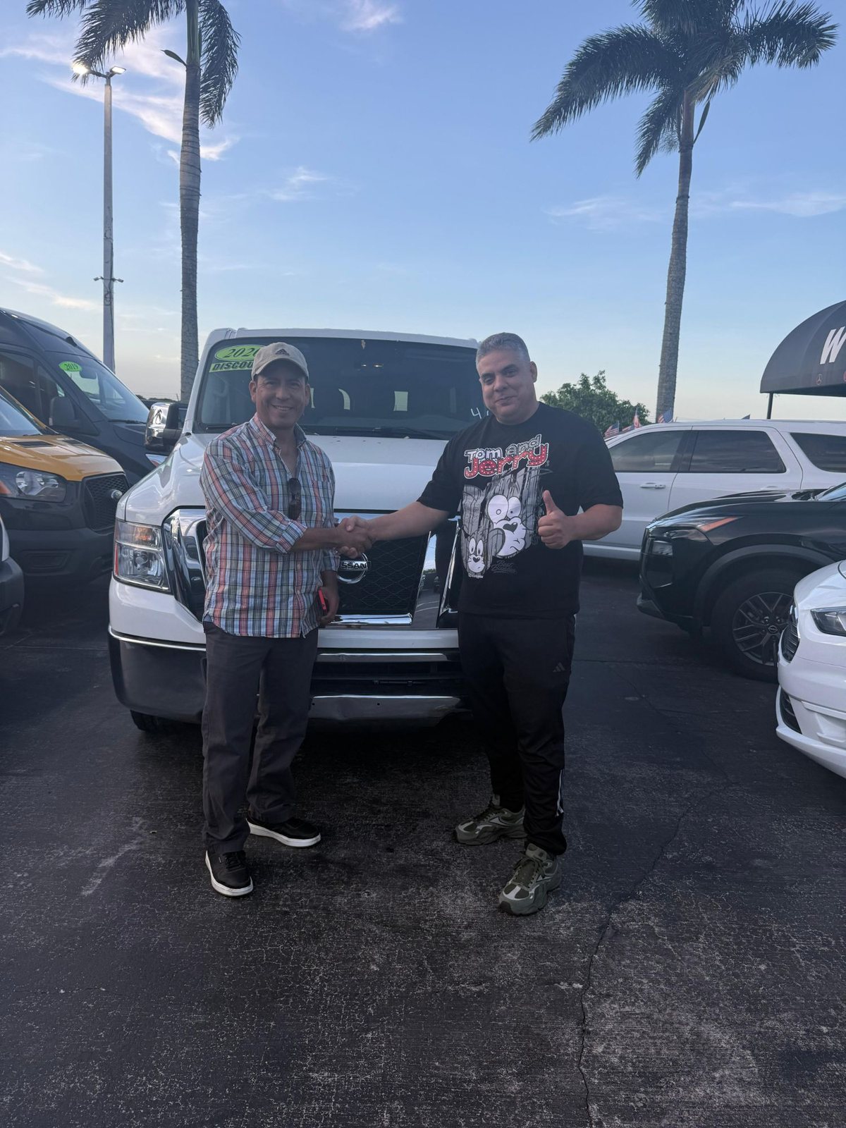 A buyer shaking hands in front of his Nissan van